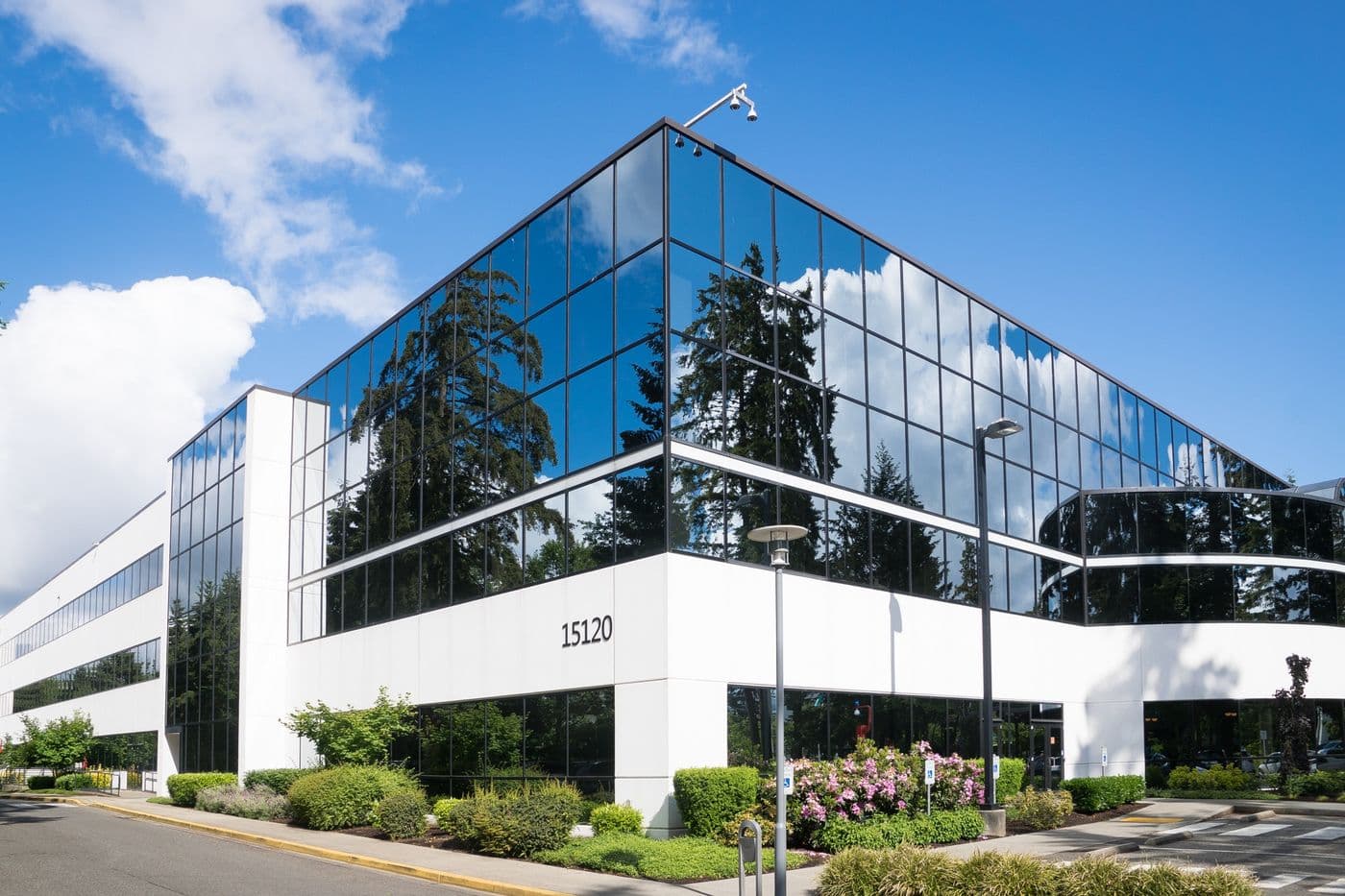 Modern glass-and-concrete office building with landscaped entrance