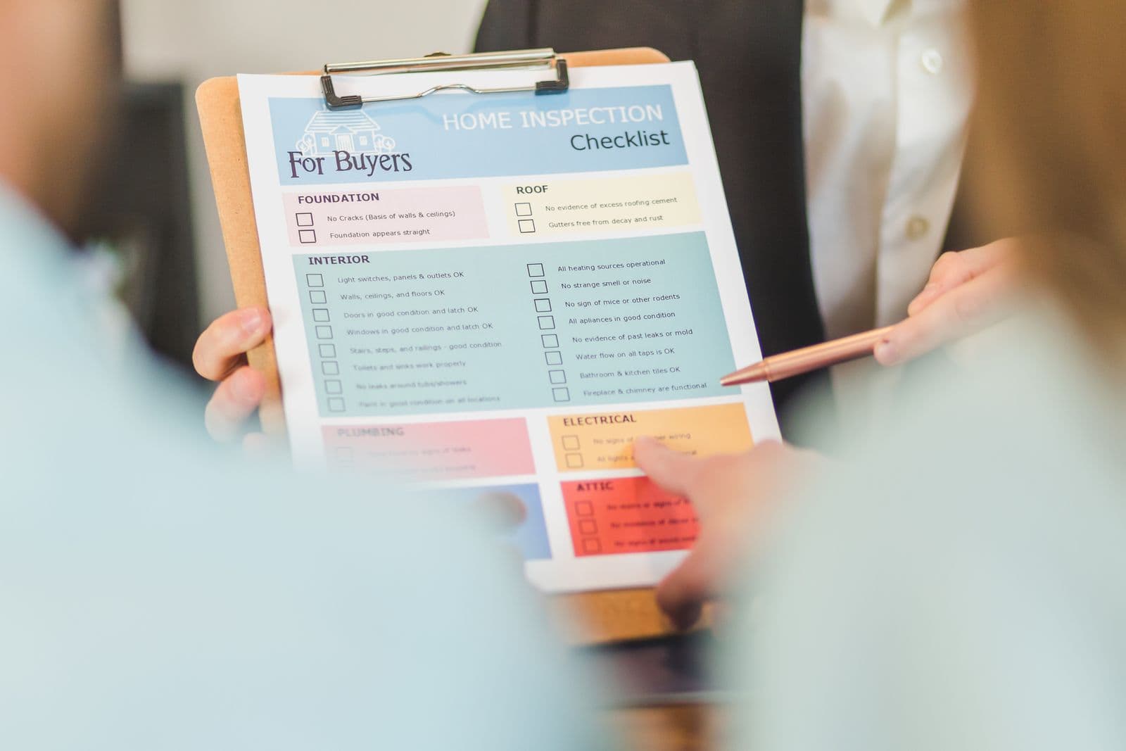 Agent reviewing a home inspection checklist on a clipboard with buyers