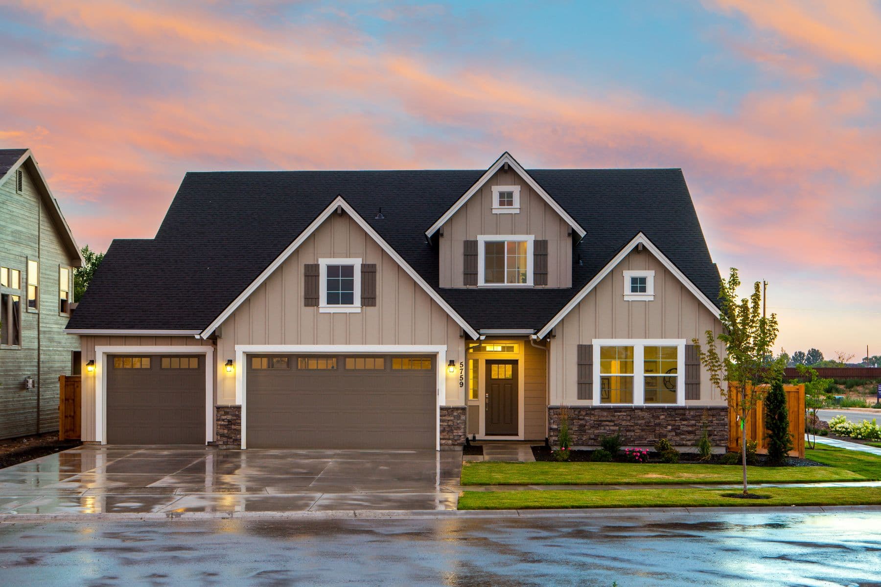 Craftsman-style home with board-and-batten siding, stone accents, and an attached garage at sunset