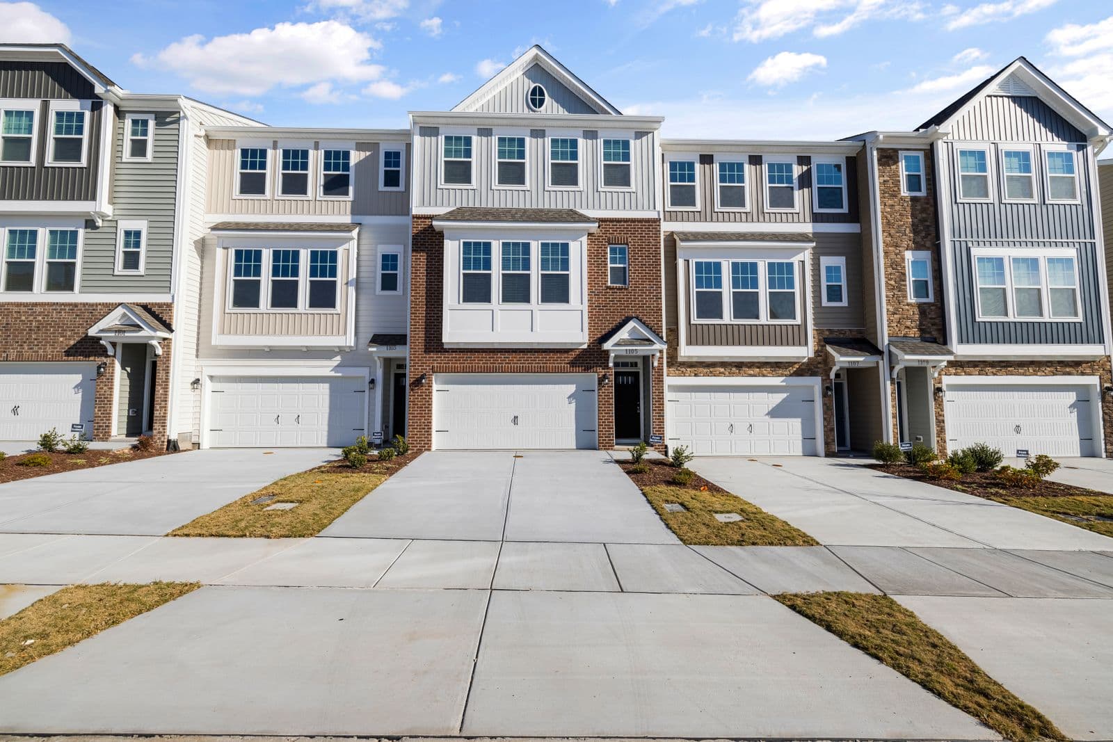 Row of attached townhomes with brick and vinyl siding and front garages